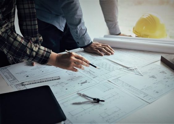 Two engineering man working with blueprints and discussing project together at the meeting in the office.